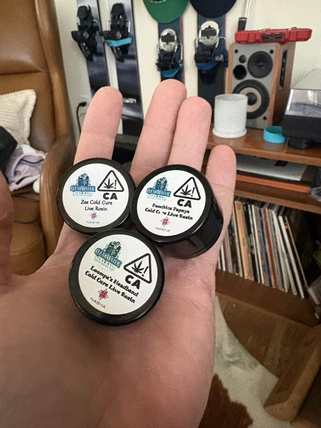 Three Nasha jars held in a hand, including Poochies Papaya