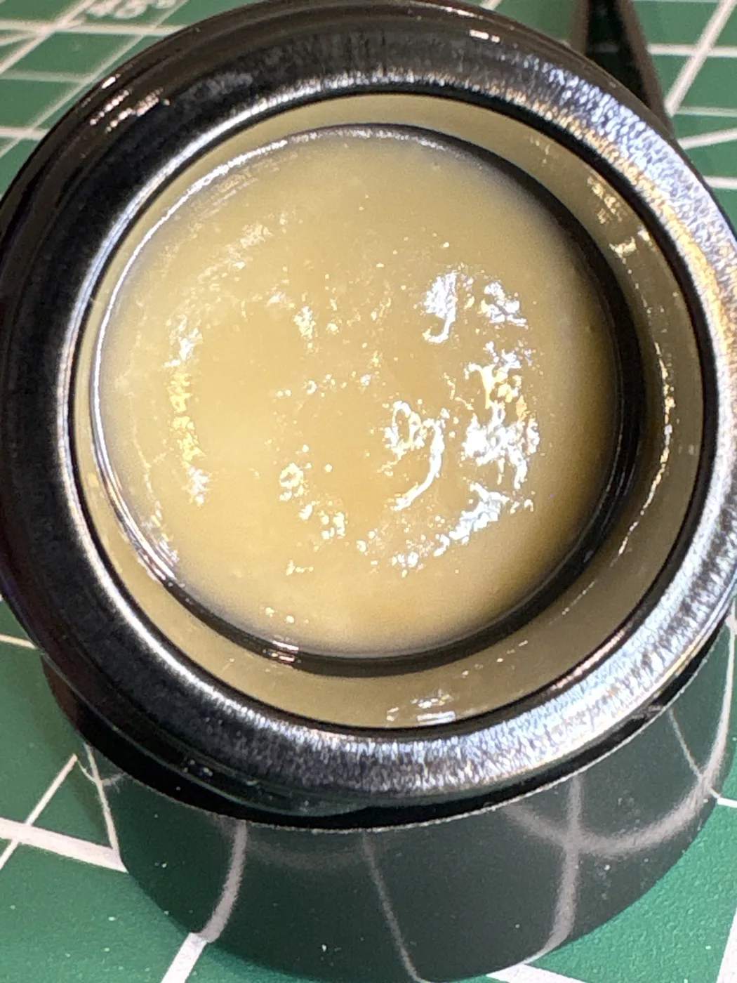 An open jar of pale, creamy Southern Press Gary Payton live rosin on a green cutting mat