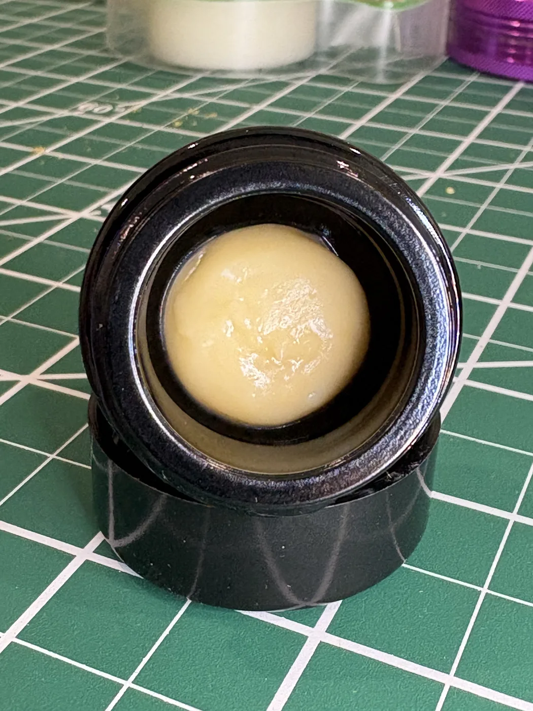 An open jar of pale, creamy Southern Press Mangosteen live rosin on a green cutting mat