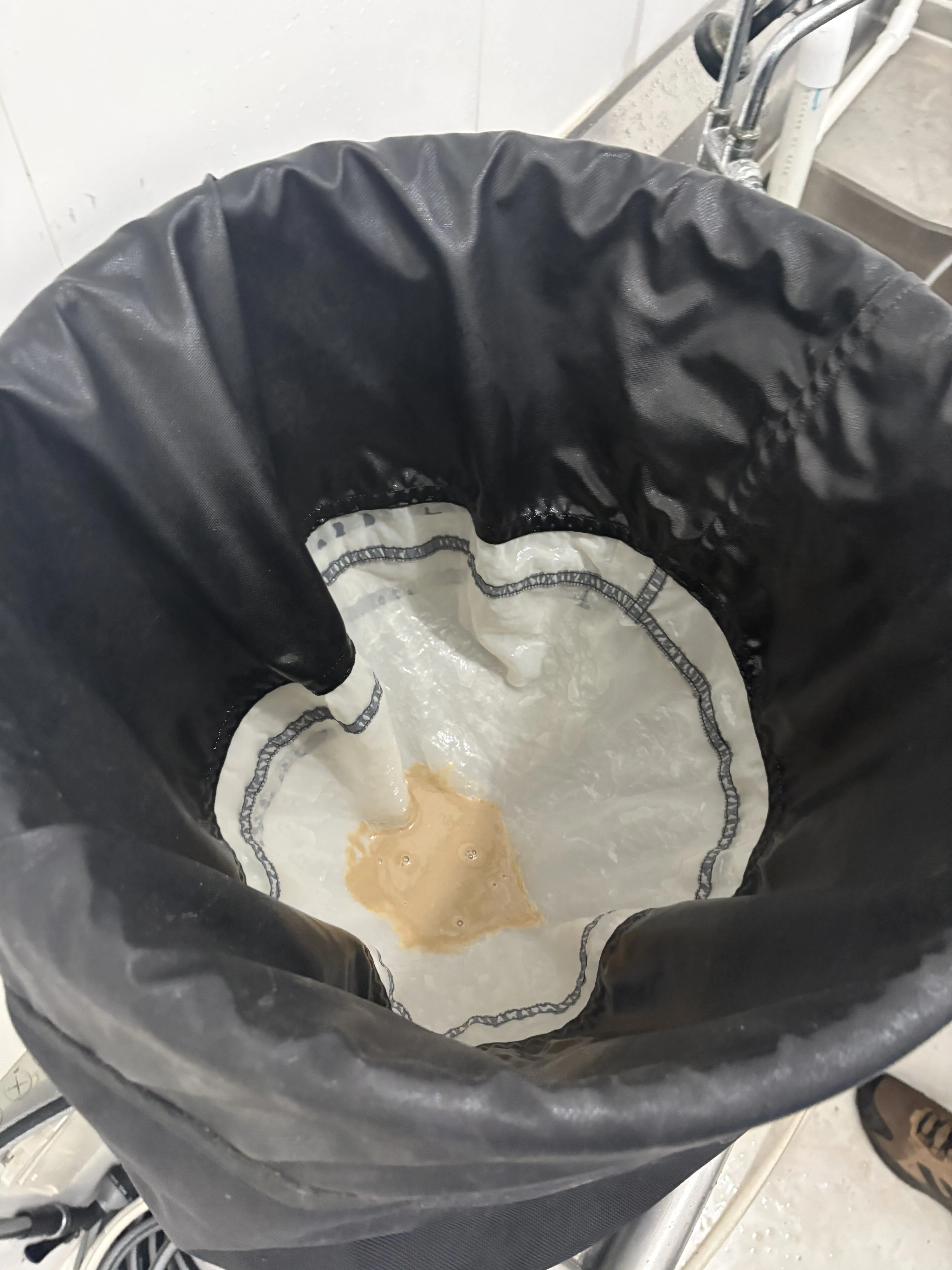 Bubble bag held open showing small golden hash yield collected on the fine mesh screen after ice water filtration